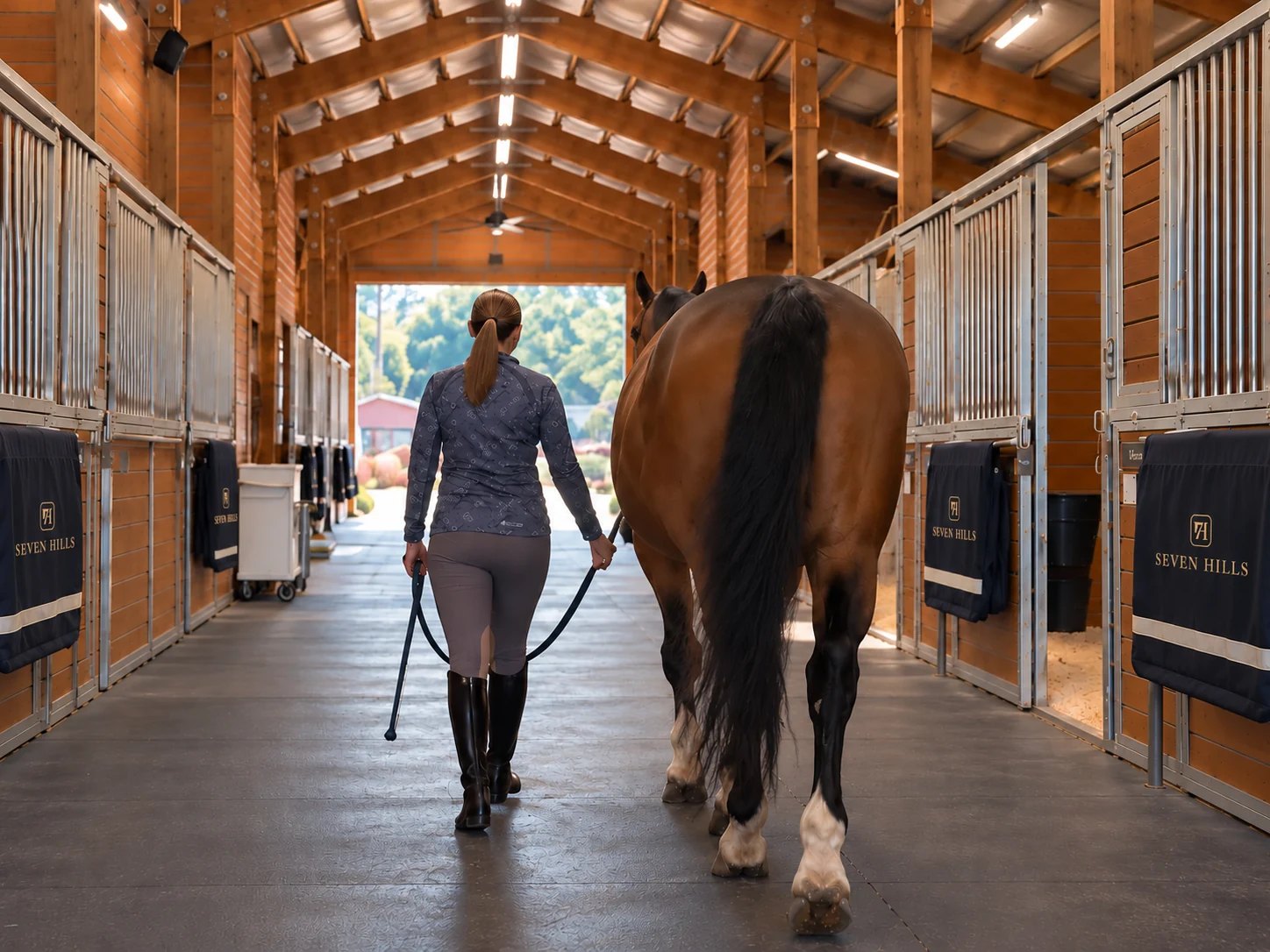 Woman leading a bay horse through the Seven Hills Training barn in Monroe, Washington